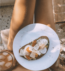 Fresh healthy foods including salmon, avocado, berries, and leafy greens displayed on a kitchen counter, representing nutrition for glowing skin health.